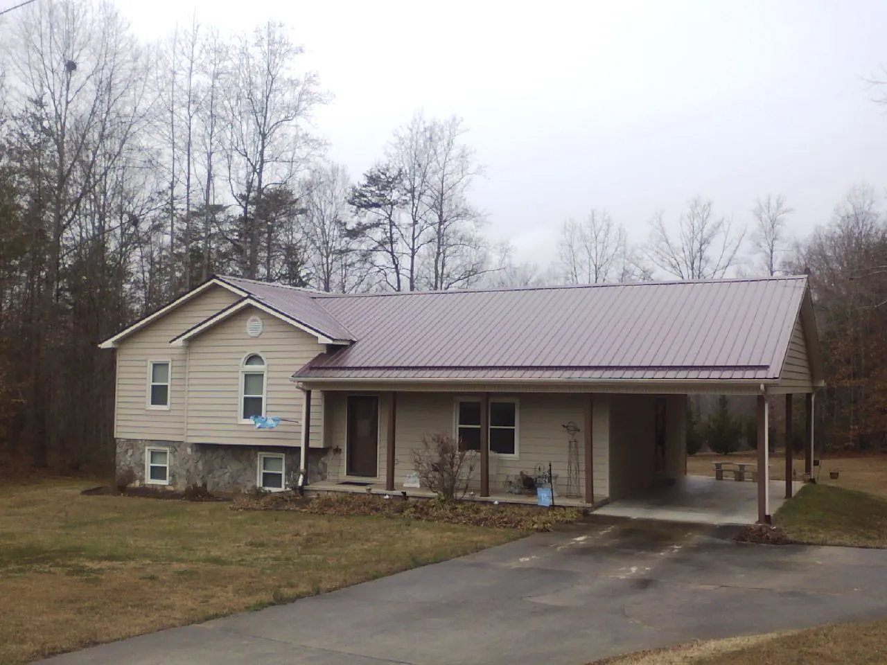 Burgundy metal roof on a tan split level home with an attached carport in Sioux Center