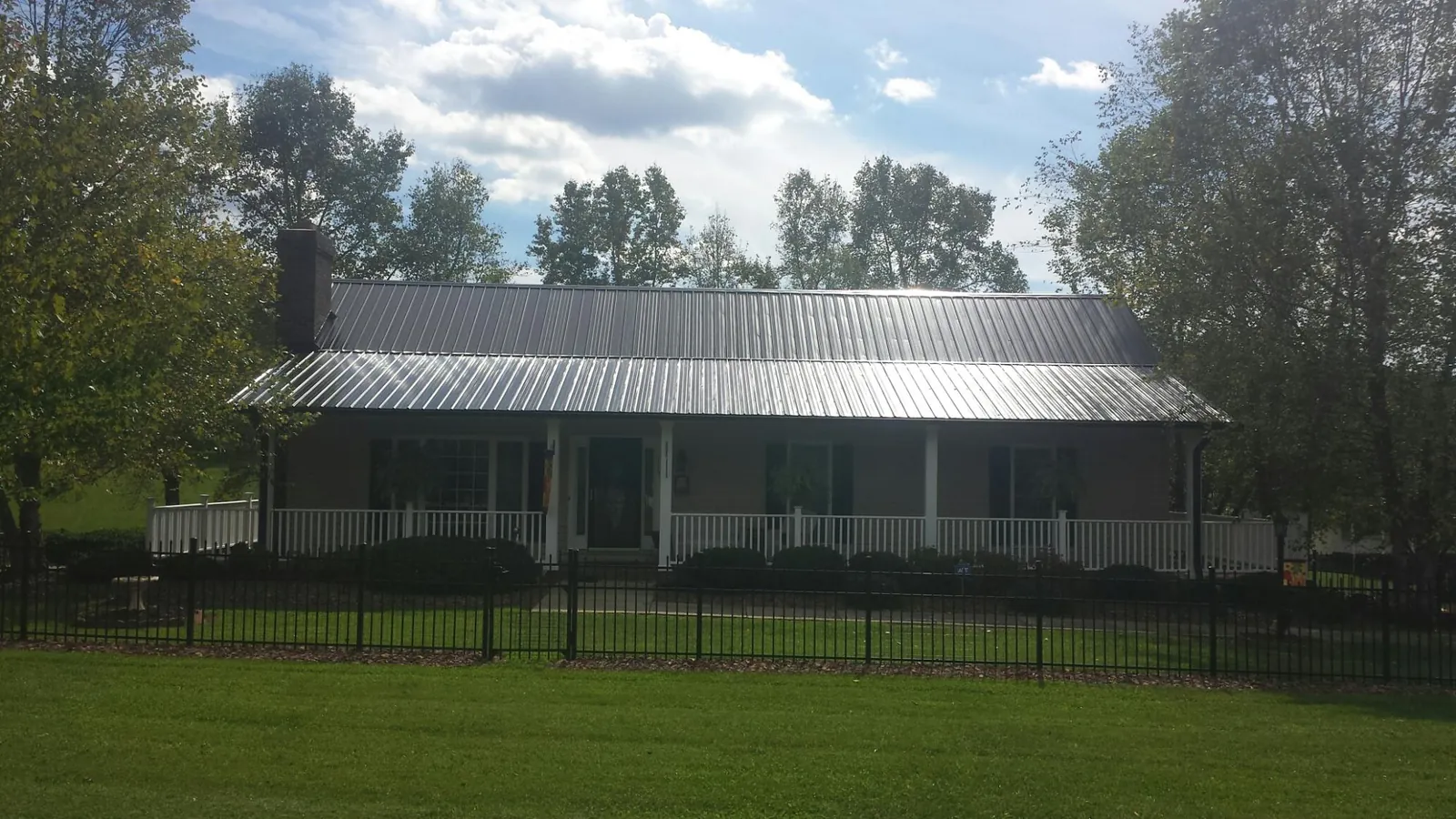 Gray metal roof on a brick ranch with a full width front porch — Gutter Guard Installation work by our crew in Sioux Center