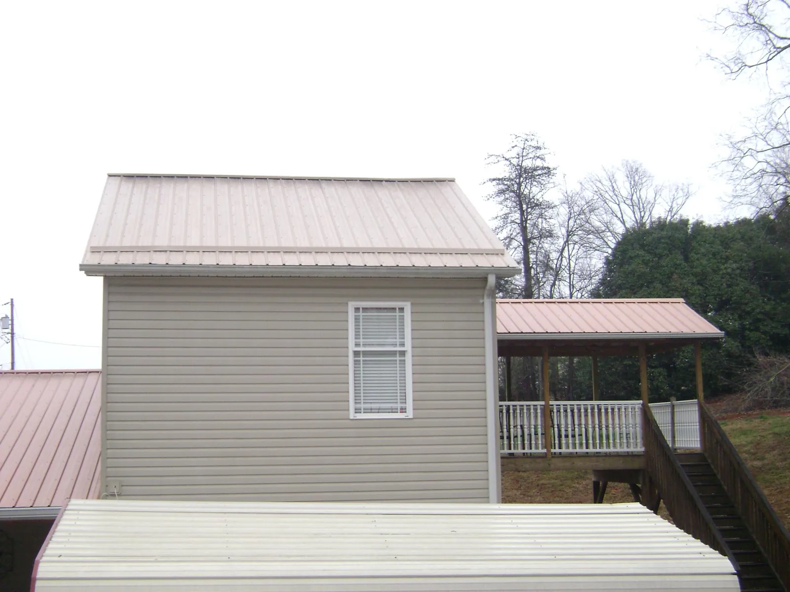 Tan metal roofs on a two story addition and attached porch, from a Roof Replacement job in Sioux Center
