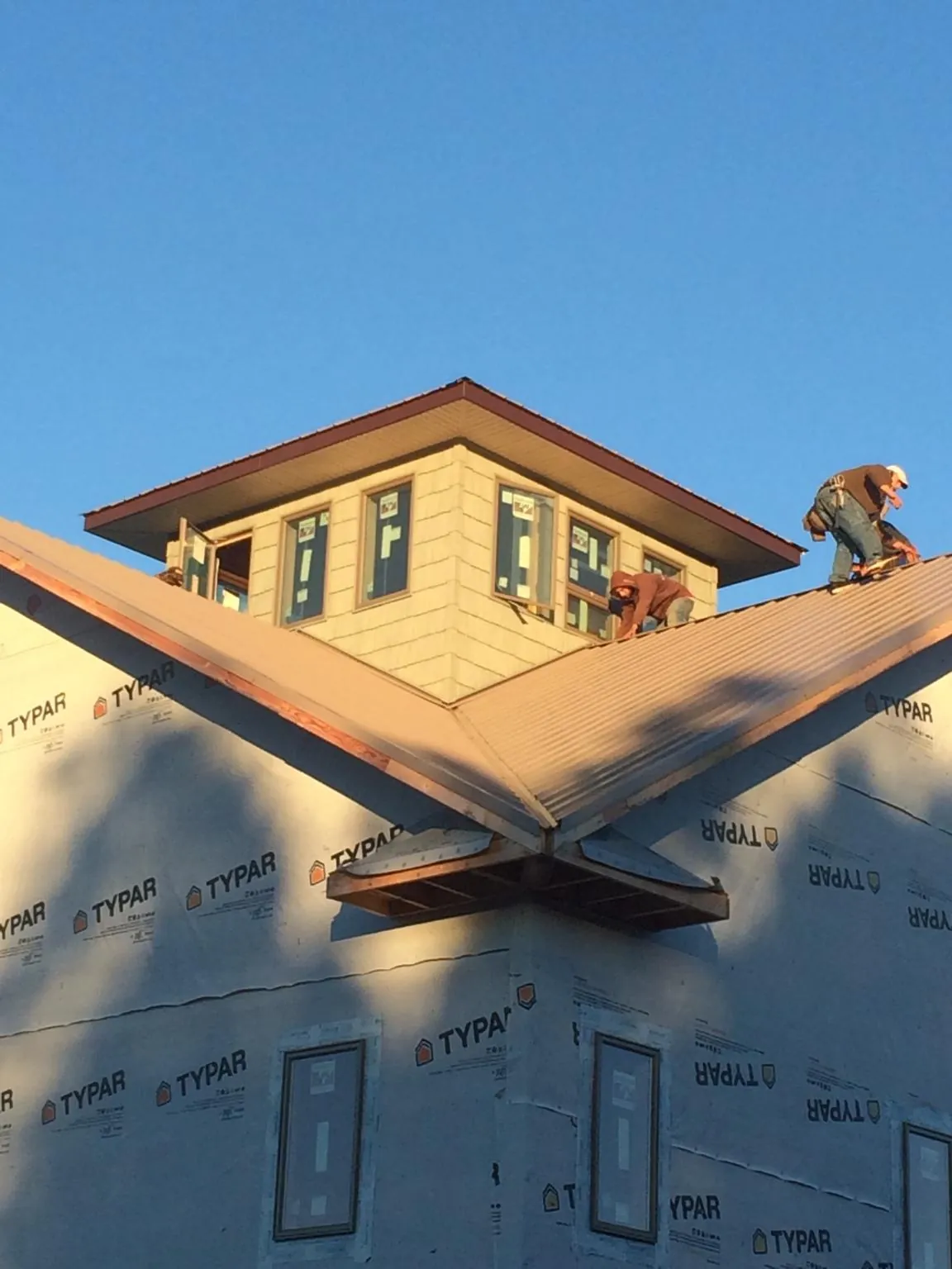 Roofers working around a rooftop cupola on a new metal roof at sunset — Roof Waterproofing in Sioux Center by Roofing Brothers